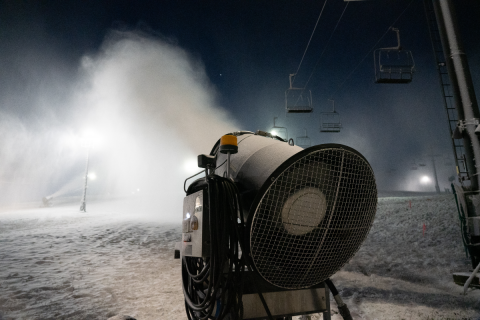 A snow gun blows fake snow onto a mountain.